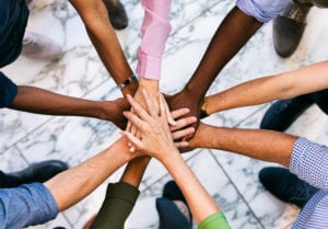 Workspace: Team Of Diverse Workers Put Hands Together A business series set in various locations in a modern workspace office building.